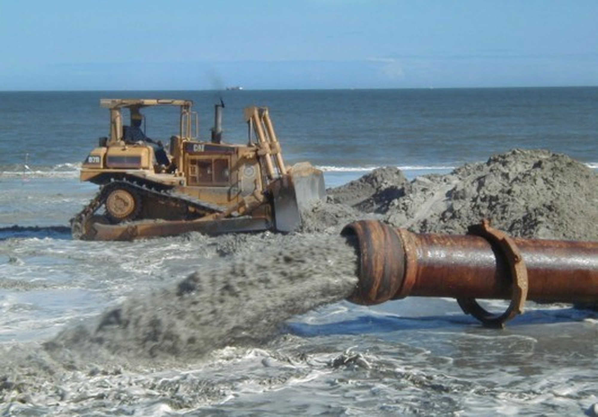 A sand pipe and bulldozer place fresh sand on Tybee Island during beach renourishment.